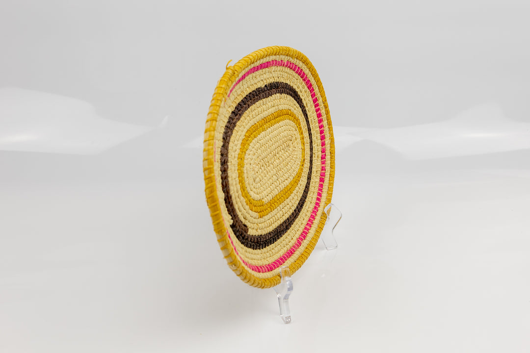 Pink, gold, brown and white. Oval design. Hand woven plate basket. Made in Panama.