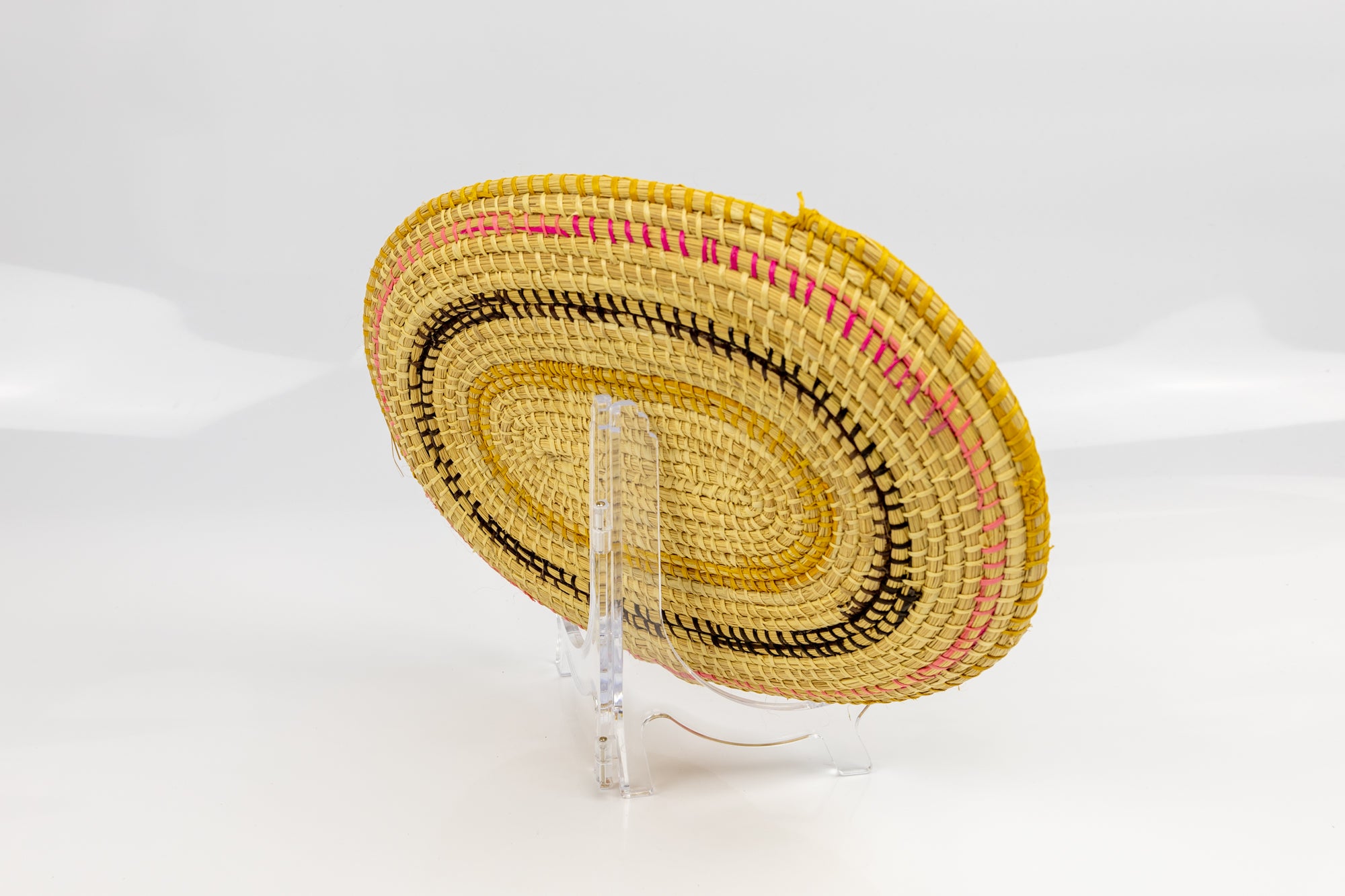 Pink, gold, brown and white. Oval design. Hand woven plate basket. Made in Panama.