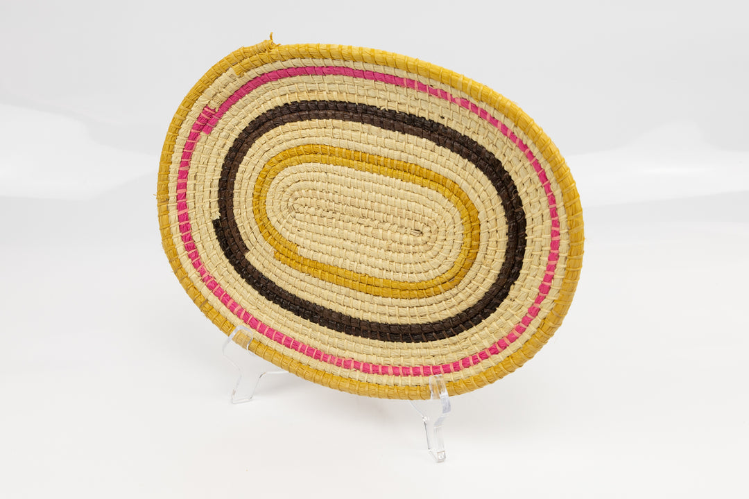 Pink, gold, brown and white. Oval design. Hand woven plate basket. Made in Panama.